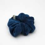Corduroy Blue scrunchie with a brand tag on a white background