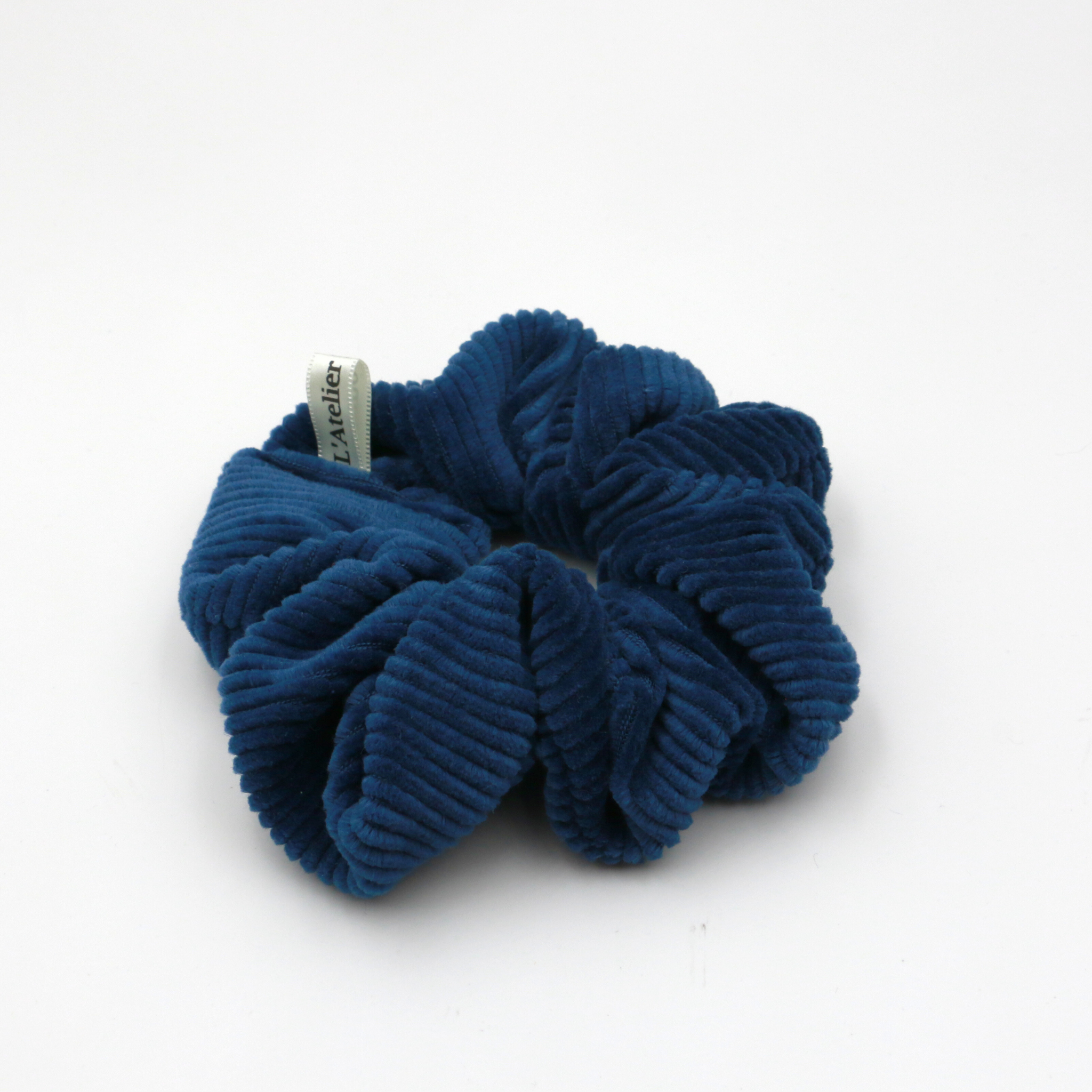 Corduroy Blue scrunchie with a brand tag on a white background