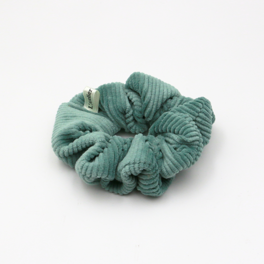 Corduroy Green scrunchie with a brand tag on a white background