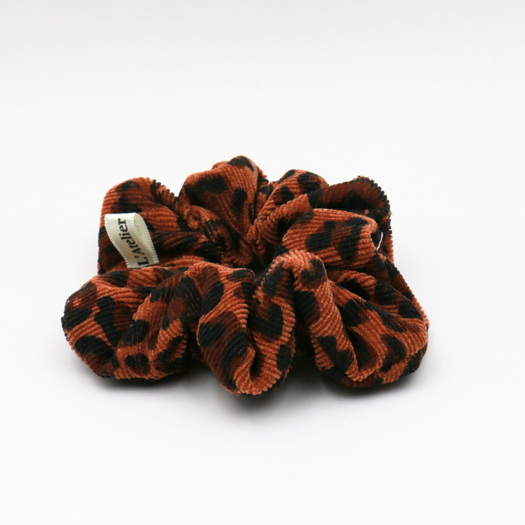 Brown and black scrunchie with a brand label on a white background