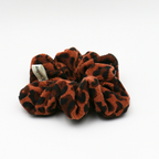 Brown and black scrunchie with a brand label on a white background