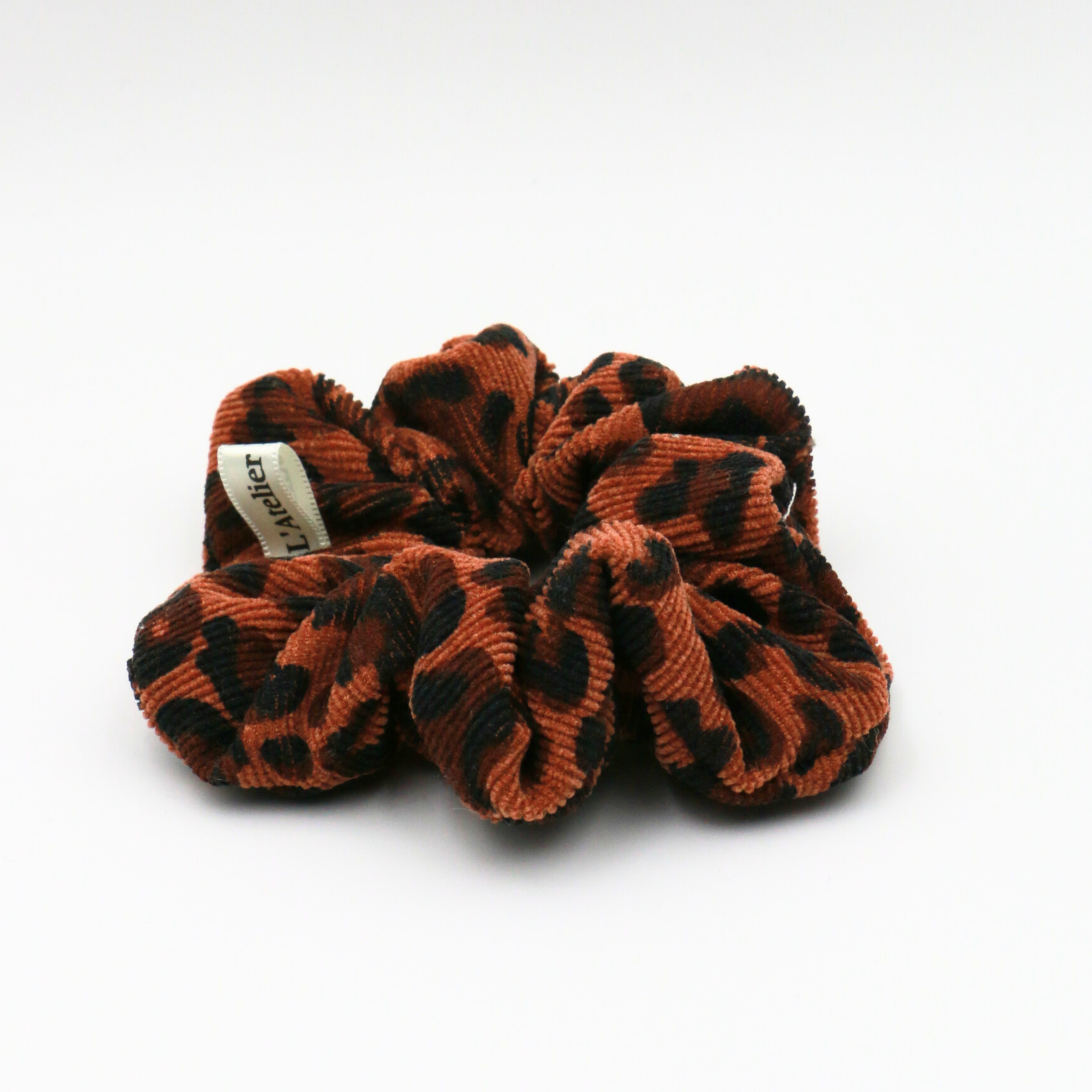 Brown and black scrunchie with a brand label on a white background