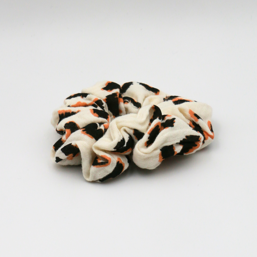 White scrunchie with black and orange pattern on a white background
