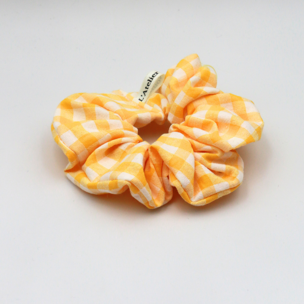 Yellow and white checkered scrunchie on a light gray background
