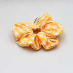 Yellow and white checkered scrunchie on a light gray background