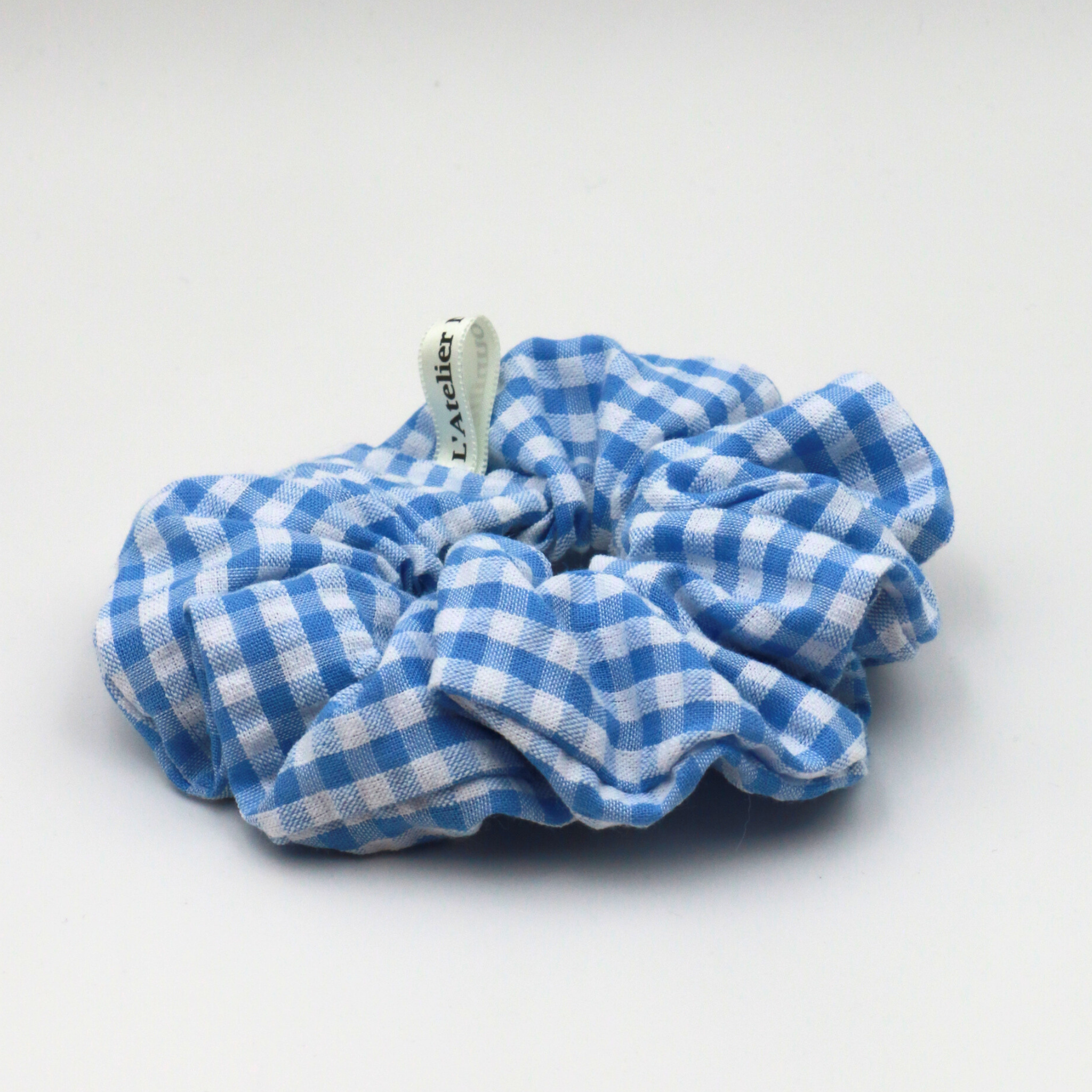 Blue and white checkered scrunchie on a light gray background