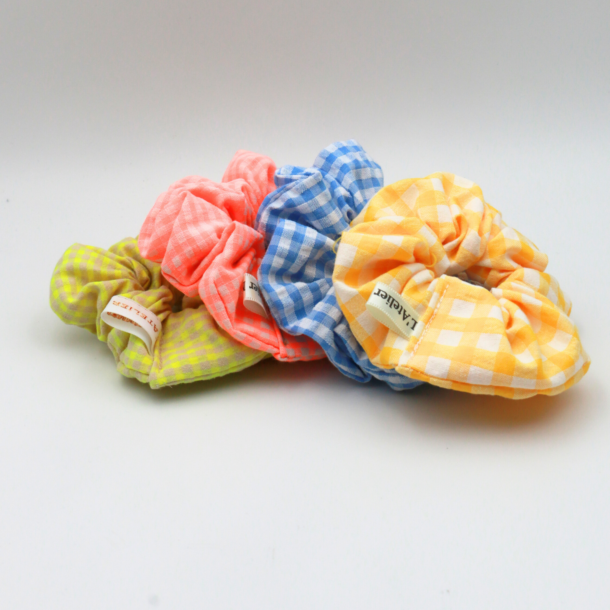 Four colorful scrunchies with checkered patterns on a white background