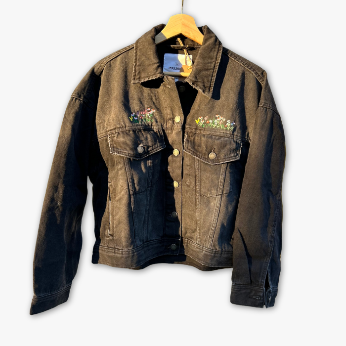 Black denim jacket with floral embroidery on a white background