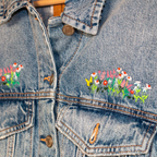 Denim jacket with floral embroidery on a wooden surface