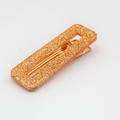 Glittery gold hair clip on a light gray background