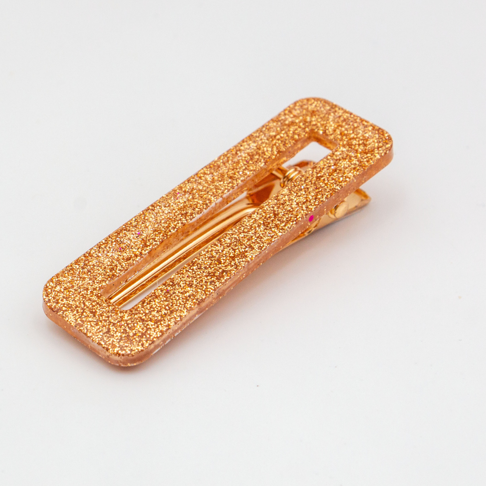 Glittery gold hair clip on a light gray background