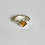 Gold ring with a honey coloured gemstone on a white background