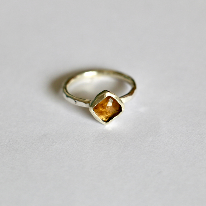 Gold ring with a honey coloured gemstone on a white background
