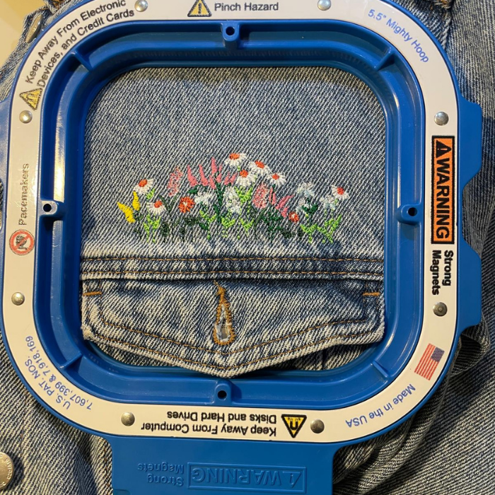 Embroidery hoop with denim fabric and floral design on a denim background